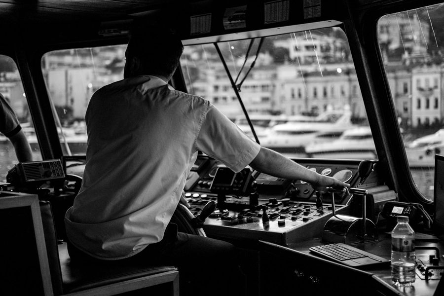 Captain at the controls of a vessel in a busy harbor, in black and white