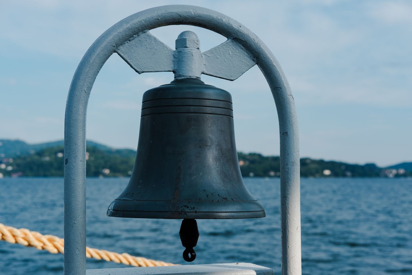 Ship’s bell mounted on deck above the sea, a symbol of the cruise ship traditions that survive at sea